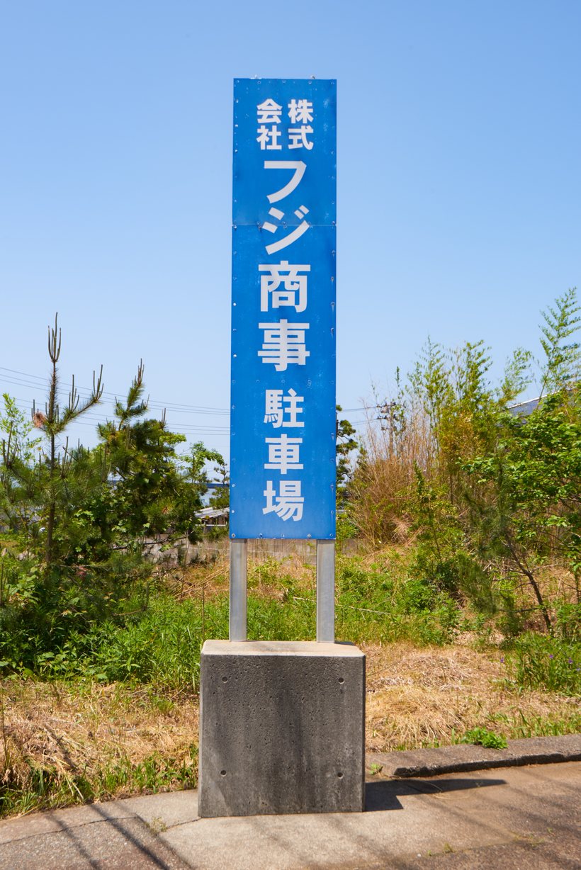 道路沿いに立つ「株式会社フジ商事 駐車場」の看板
